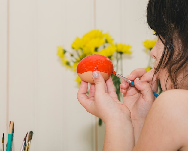 Chica de cultivo pintando huevo con naranja