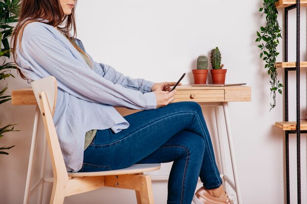 Chica de cultivo con smartphone en la mesa de trabajo