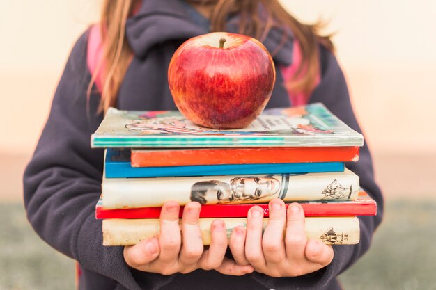 Chica de cultivos con libros y manzana