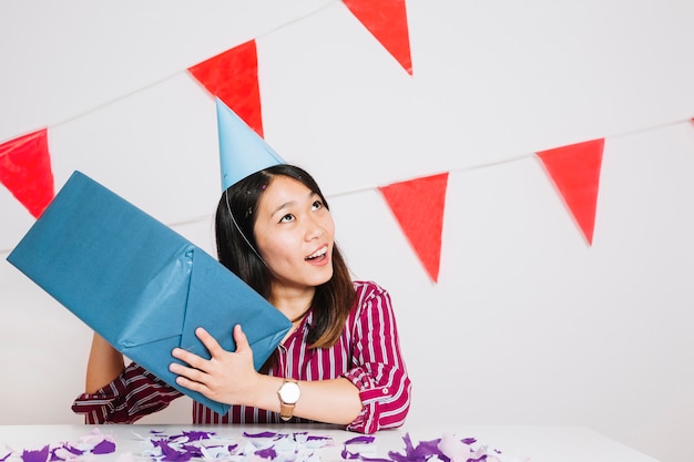 Chica de cumpleaños moviendo caja de regalos