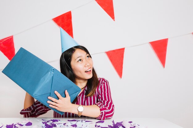 Chica de cumpleaños moviendo caja de regalos