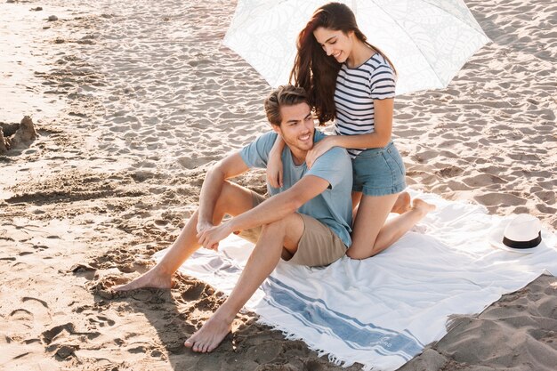 Chica dando masaje al novio en la playa