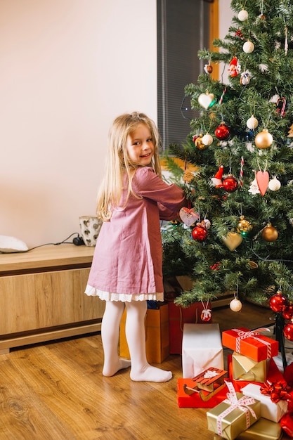 Chica decorando árbol de navidad en salón