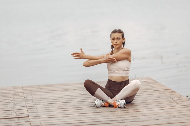 Chica de deportes por el agua. Mujer en un parque de verano. Dama en ropa deportiva.