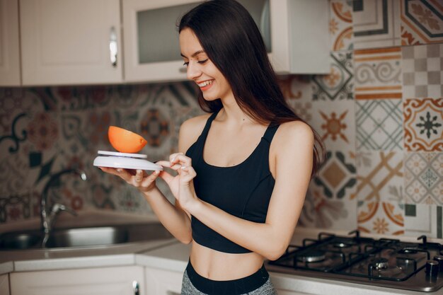 Chica de deportes en una cocina con frutas.