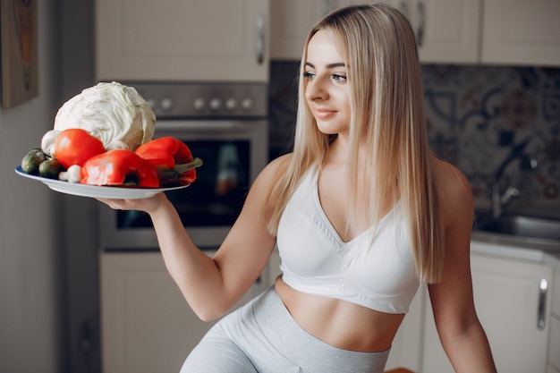 Chica de deportes en una cocina con frutas.