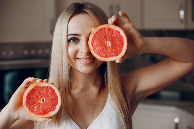 Chica de deportes en una cocina con frutas.