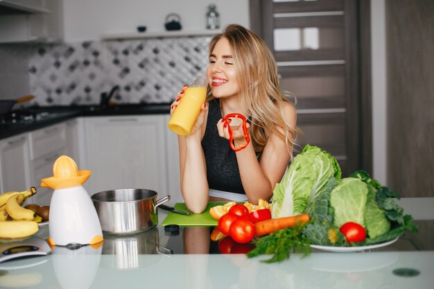 Chica de deportes en una cocina con verduras