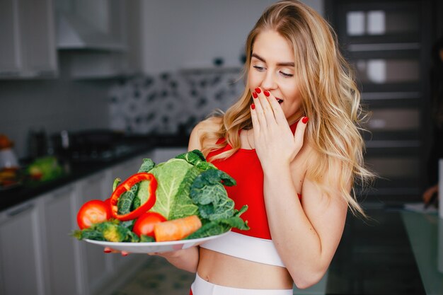 Chica de deportes en una cocina con verduras