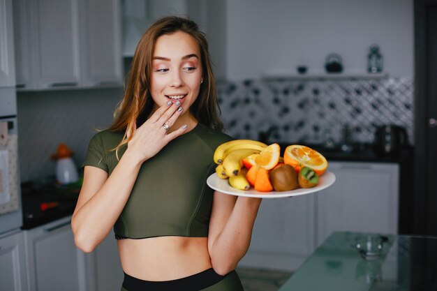 Chica de deportes en una cocina con verduras