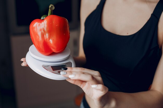 Chica de deportes en una cocina con verduras