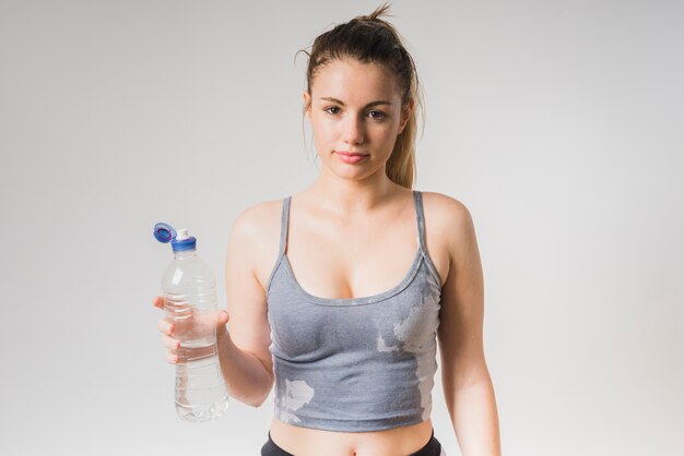 Chica deportista mojada con botella de agua