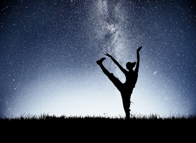 Una chica deportiva al amanecer se dedica al yoga. Clases de fitness en starry sky