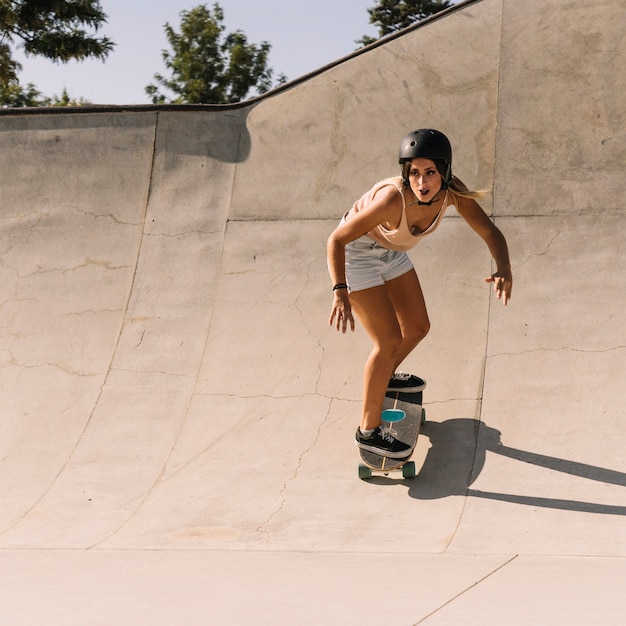 Chica deportiva con casco skating en medio tubo