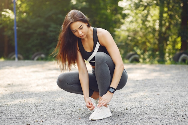 Chica deportiva en un entrenamiento top negro en un parque de verano