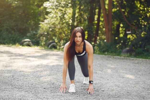 Chica deportiva en un entrenamiento top negro en un parque de verano