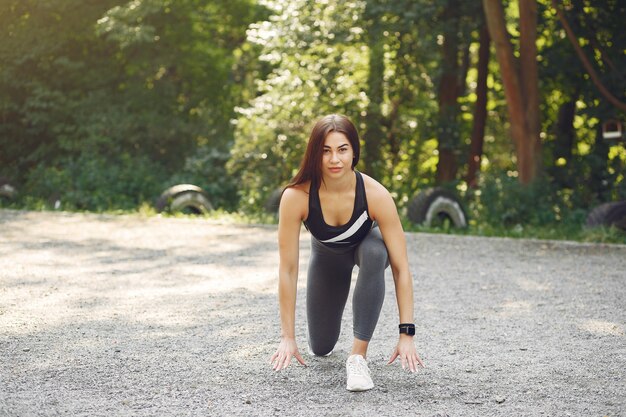 Chica deportiva en un entrenamiento top negro en un parque de verano