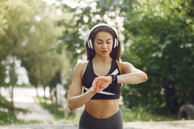 Chica deportiva entrenando con auriculares en un parque de verano