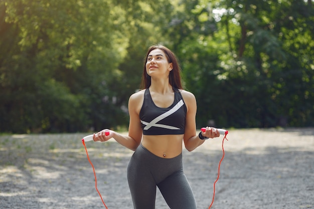 Chica deportiva entrenando con saltar la cuerda en un parque de verano
