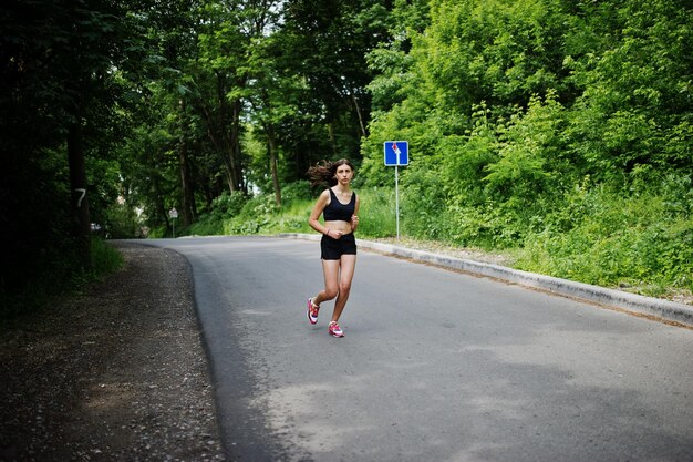 Chica deportiva en ropa deportiva corriendo en un parque verde y entrenando en la naturaleza Un estilo de vida saludable