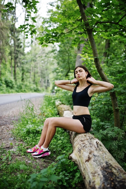 Chica deportiva en ropa deportiva descansando en un parque verde después de entrenar en la naturaleza Un estilo de vida saludable