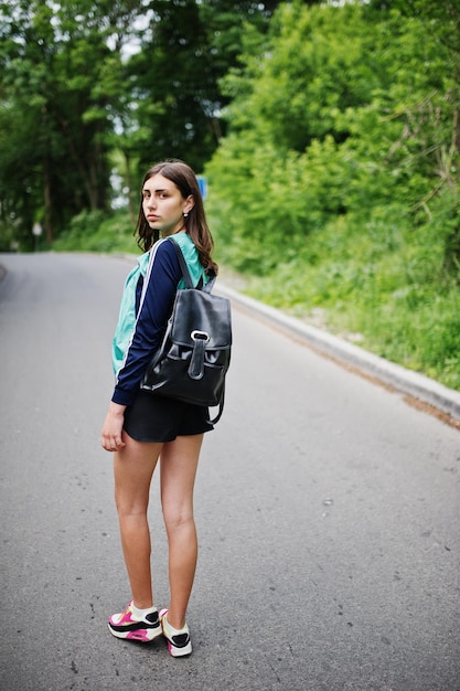Chica deportiva en ropa deportiva con mochila caminando en un parque verde Un estilo de vida saludable