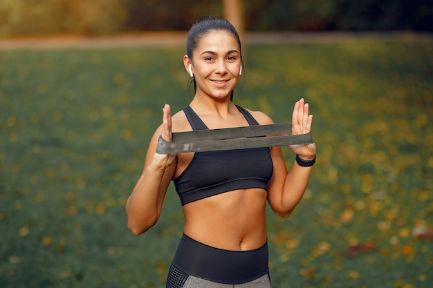 Foto gratuita chica deportiva en un top negro entrenamiento en un parque de otoño