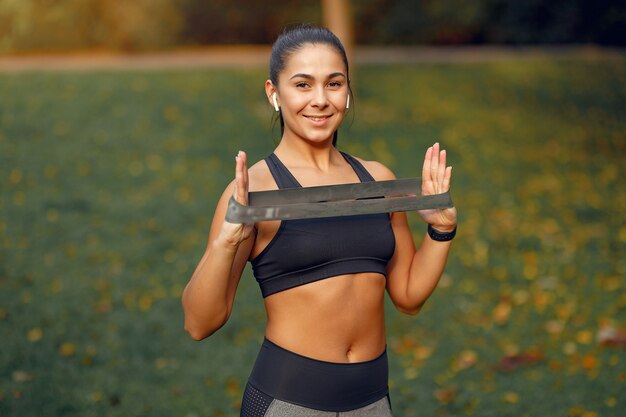 Chica deportiva en un top negro entrenamiento en un parque de otoño