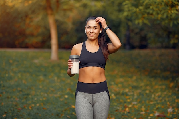 Chica deportiva en un top negro entrenamiento en un parque de otoño