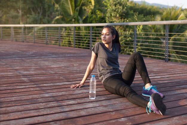 Chica descansando junto a una botella de agua