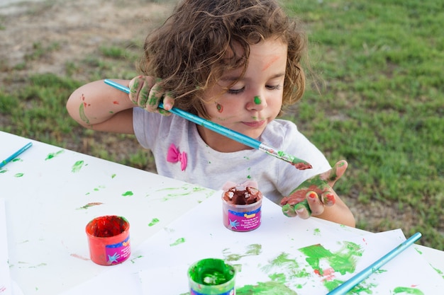 Foto gratuita chica desordenada pintura sobre lienzo en el parque