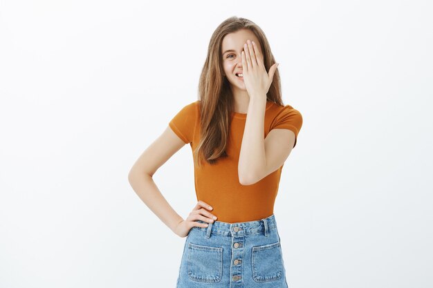 Chica despreocupada cubre la mitad de la cara y sonriendo