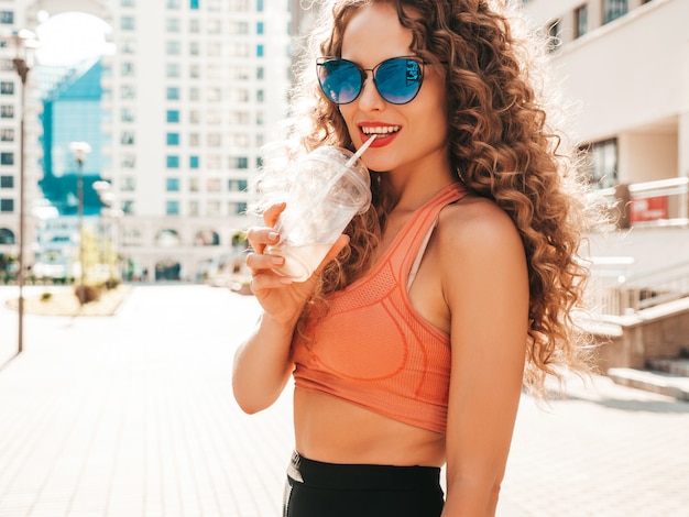 Chica despreocupada posando en la calle con una bebida