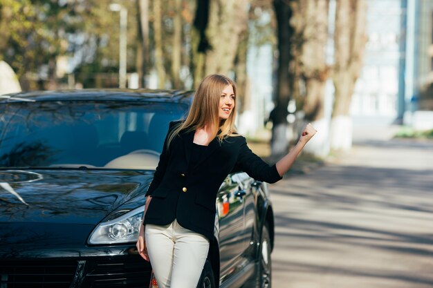 Chica detiene coches cerca de su coche destrozado