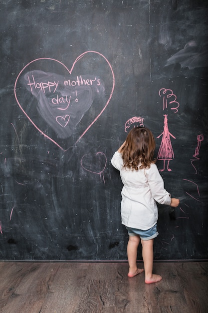 Foto gratuita chica dibujando cerca de la inscripción feliz día de la madre