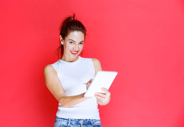 Chica dibujando en un cuaderno de bocetos en blanco.