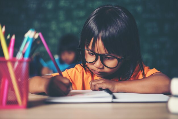 chica con dibujo de lápices de colores en la lección en el aula