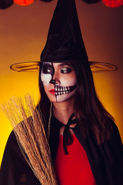 Foto gratuita chica en disfraz de halloween sujetando escoba