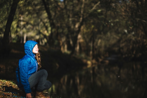 Chica disfrutando el clima cerca del estanque