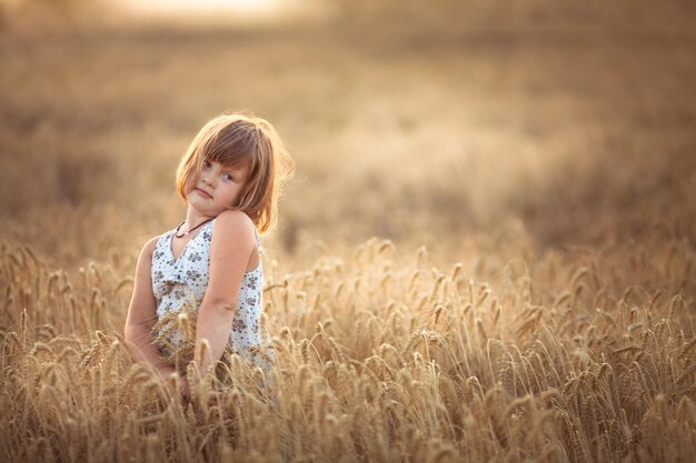 Chica divertida baila en el campo con centeno al atardecer