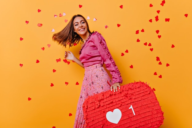 Chica divertida en blusa rosa bailando. Increíble modelo caucásico disfrutando de una sesión de retratos con confeti.