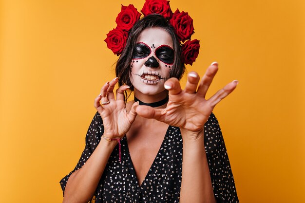 La chica divertida gruñe y muestra las uñas como un gato. Retrato de hermosa mexicana con maquillaje para halloween.