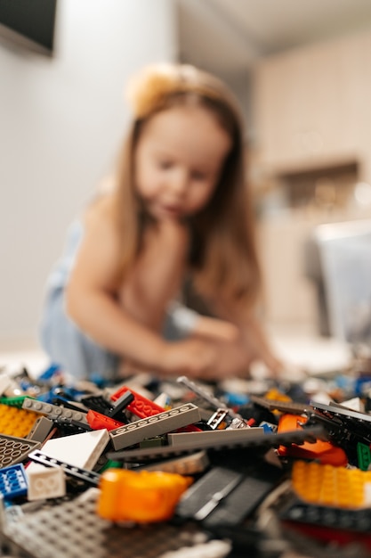 Chica divertida y linda jugando lego en casa en el suelo, se centran en los juguetes. Estilo de vida del primer rol educativo