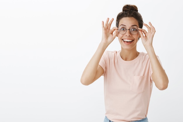 Foto gratuita chica divertida y sorprendida con gafas posando contra la pared blanca