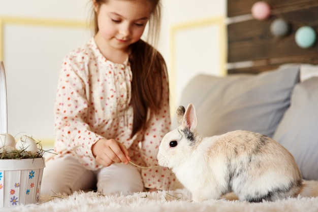 Chica divirtiéndose con conejo en la cama