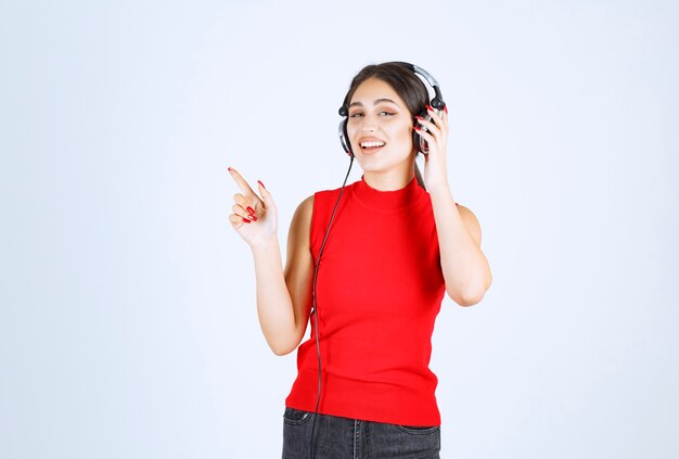 Chica de DJ con auriculares apuntando a él.