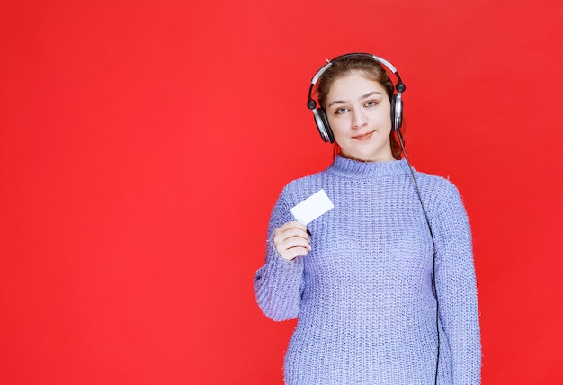 Chica Dj con auriculares presentando su tarjeta de visita.