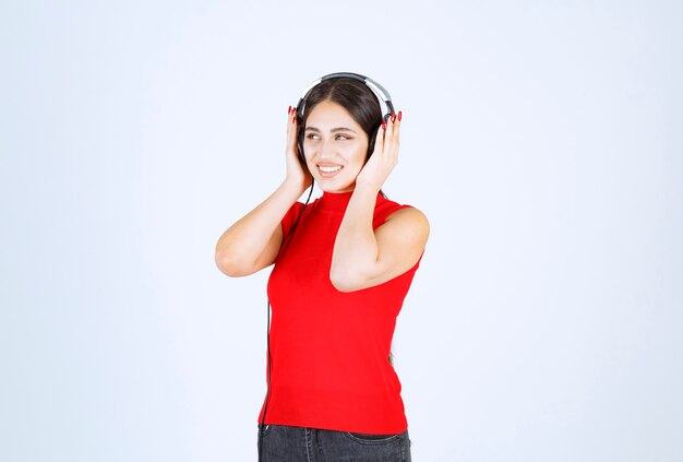 Chica Dj en camisa roja con audífonos y escuchando una buena música.