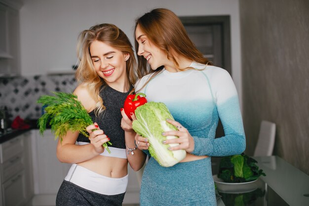 Chica de dos deportes en una cocina con verduras