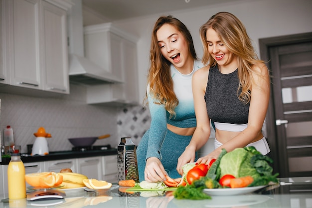 Chica de dos deportes en una cocina con verduras